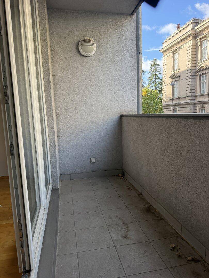 Kleiner Balkon mit Fliesenboden und Blick auf die umliegenden Gebäude.