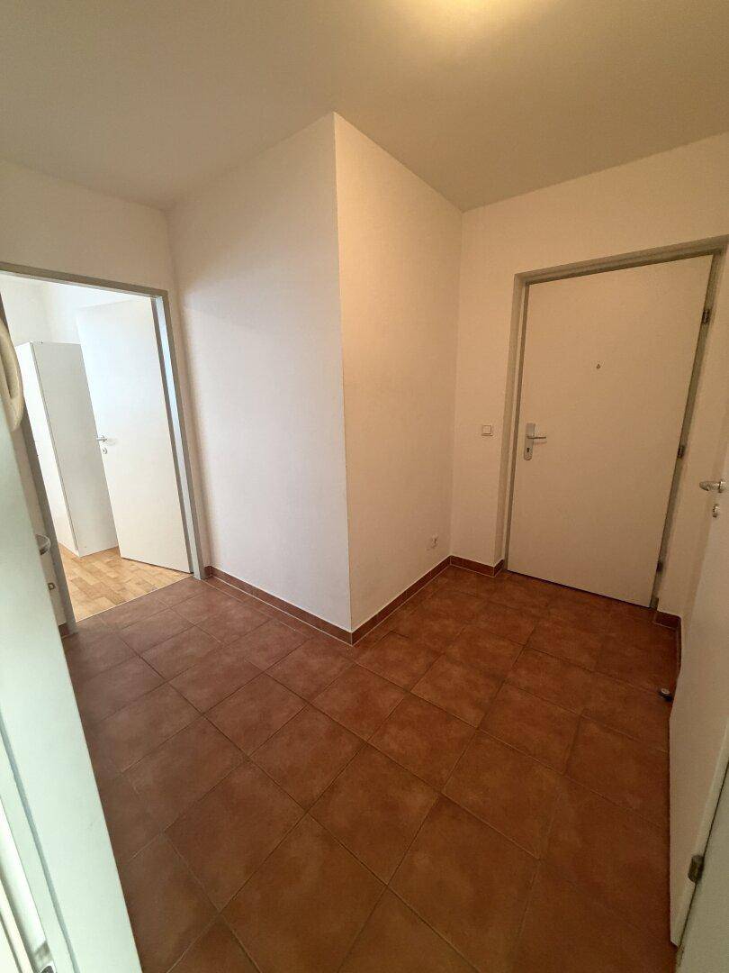 Heller Flur mit Terrakotta-Fliesenboden und Zugang zu verschiedenen Räumen.
