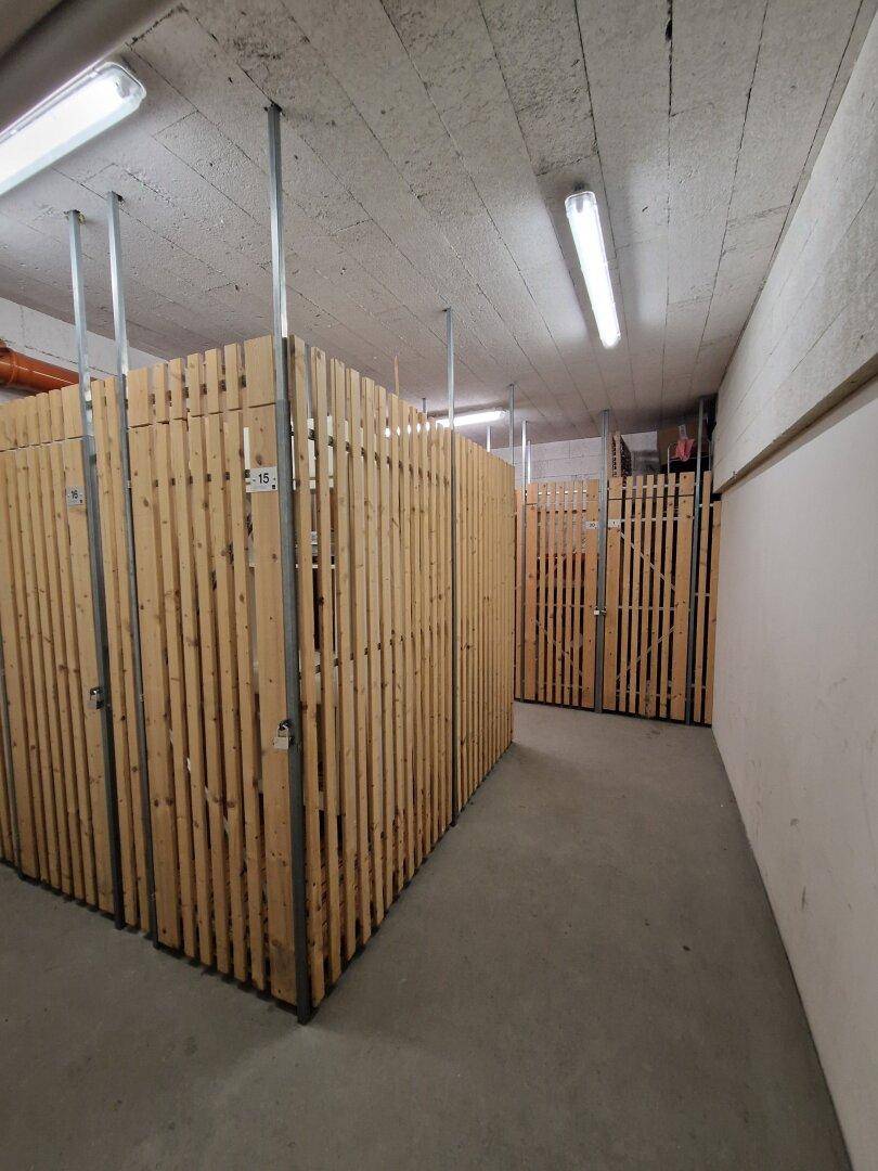 Abstellräume im Kellerbereich mit Holzverschlägen für zusätzlichen Stauraum.