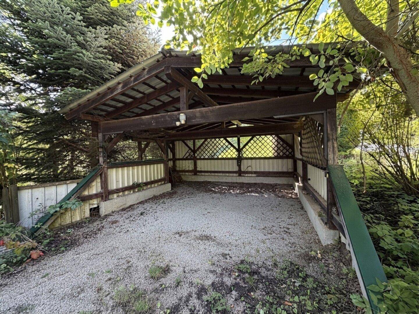 Geräumiger Carport mit Holzbalkenkonstruktion, bietet geschützten Parkraum.