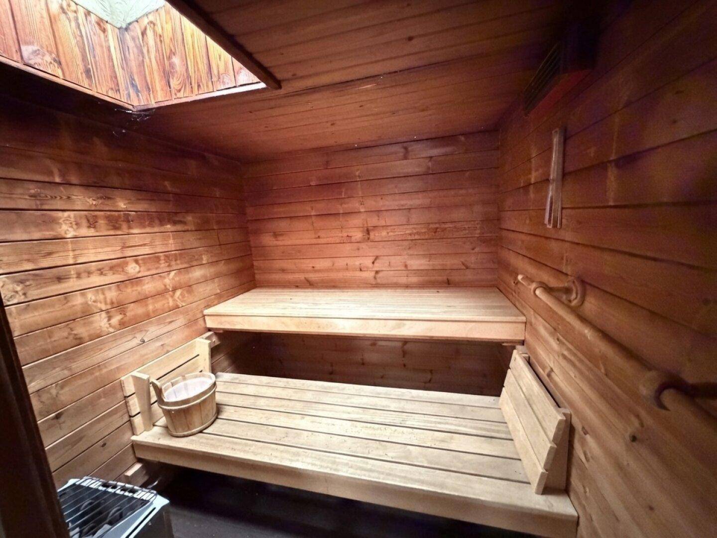 Gemütliche Holzsauna mit zwei Bänken und einem Saunaofen, ideal zur Entspannung.