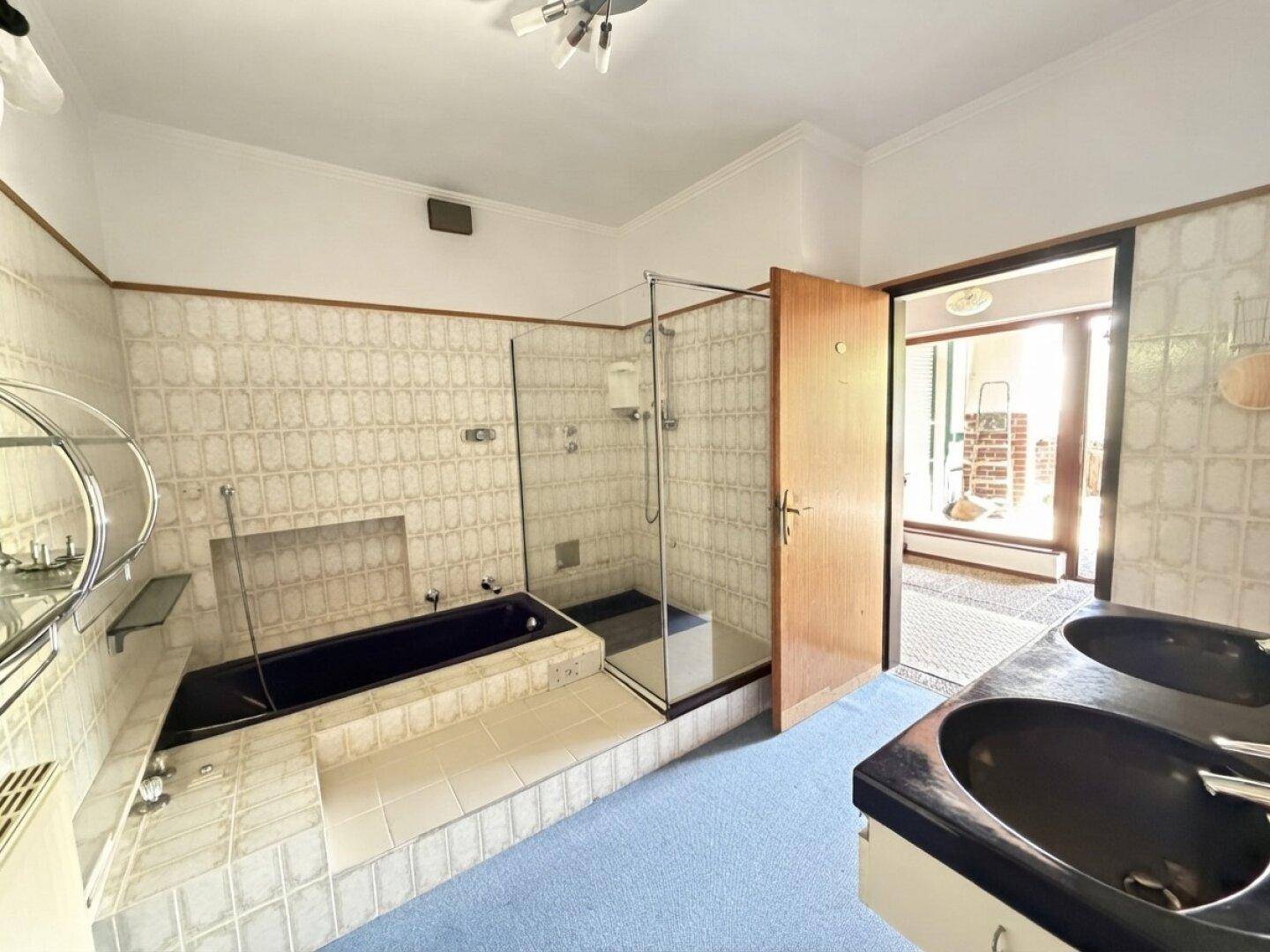 Geräumiges Badezimmer mit Doppelwaschbecken, Badewanne und Dusche, im Stil der 80er Jahre.