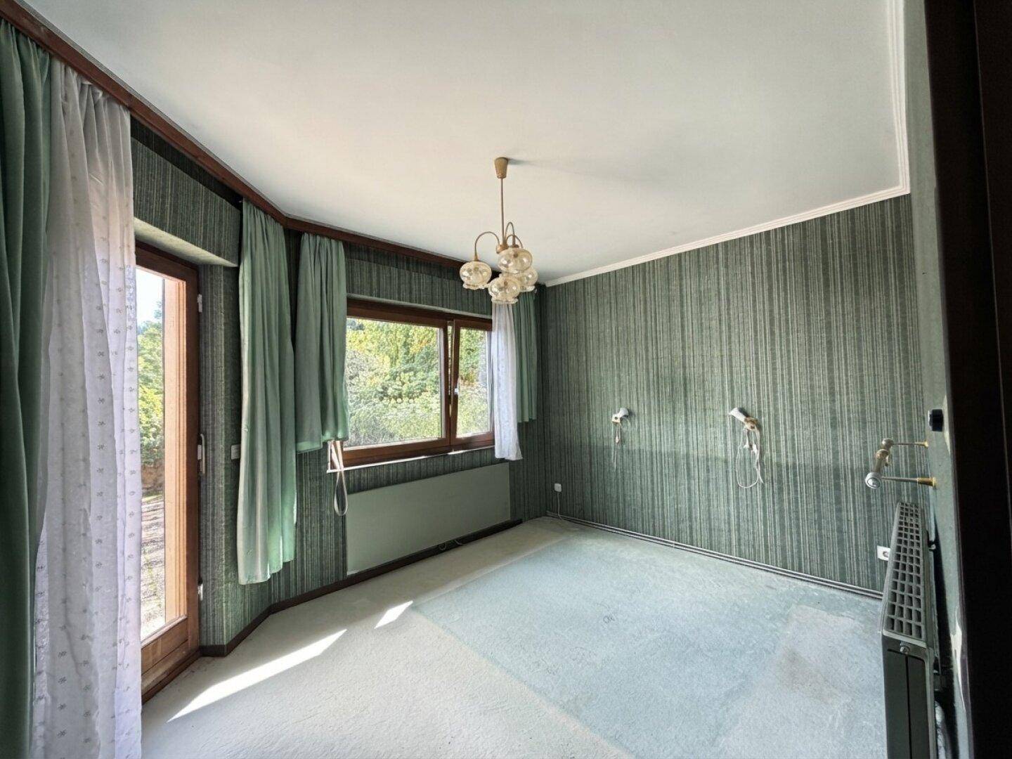 Schlafzimmer mit grüner Tapete, Teppichboden und Zugang zu einem Balkon oder Terrasse.