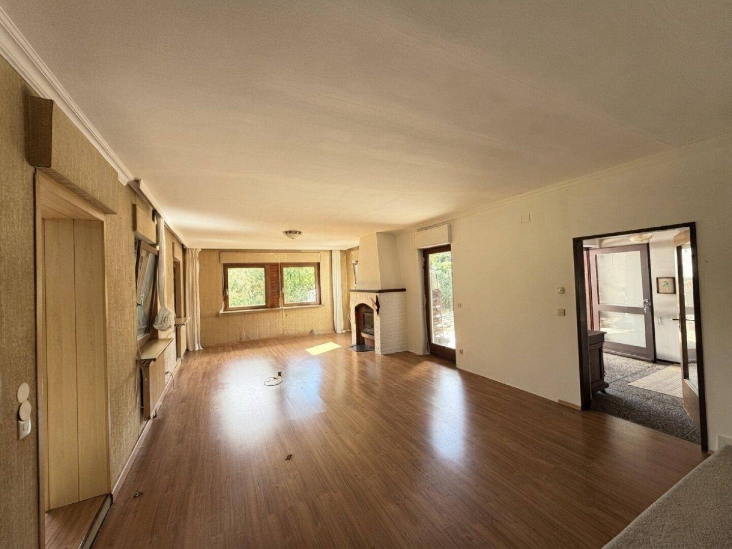 Helles Wohnzimmer mit Holzboden und einem gemütlichen Kamin, ideal für kalte Tage.