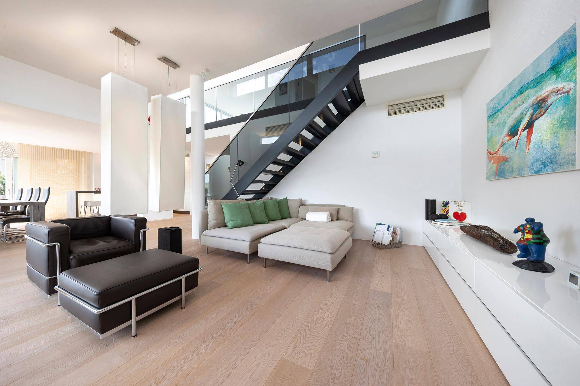 Geräumiges Wohnzimmer mit stilvollen Sofas, Kunstwerken und eleganter Treppe.