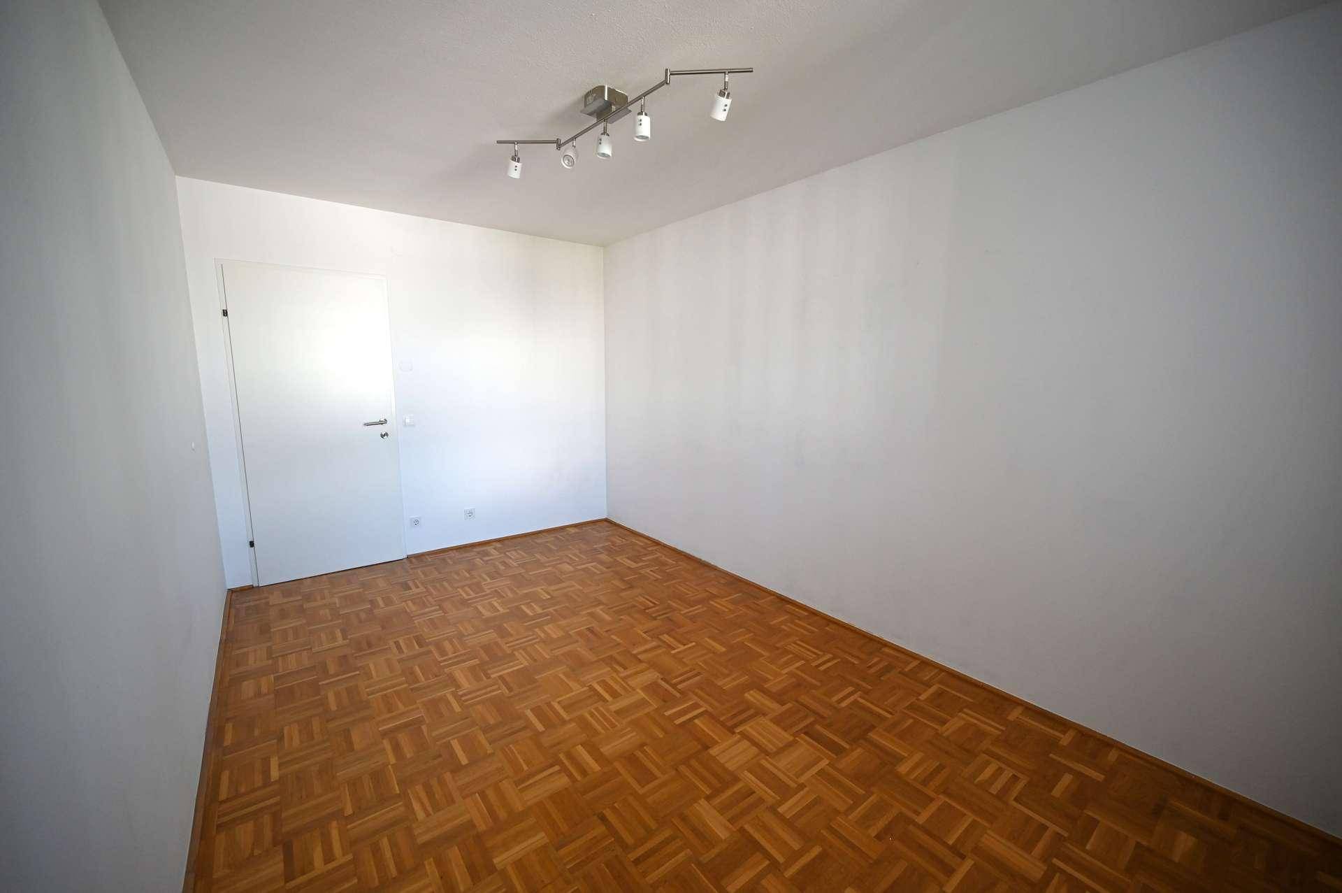Geräumiges Schlafzimmer mit Parkettboden und weißen Wänden, ideal für individuelle Einrichtung.