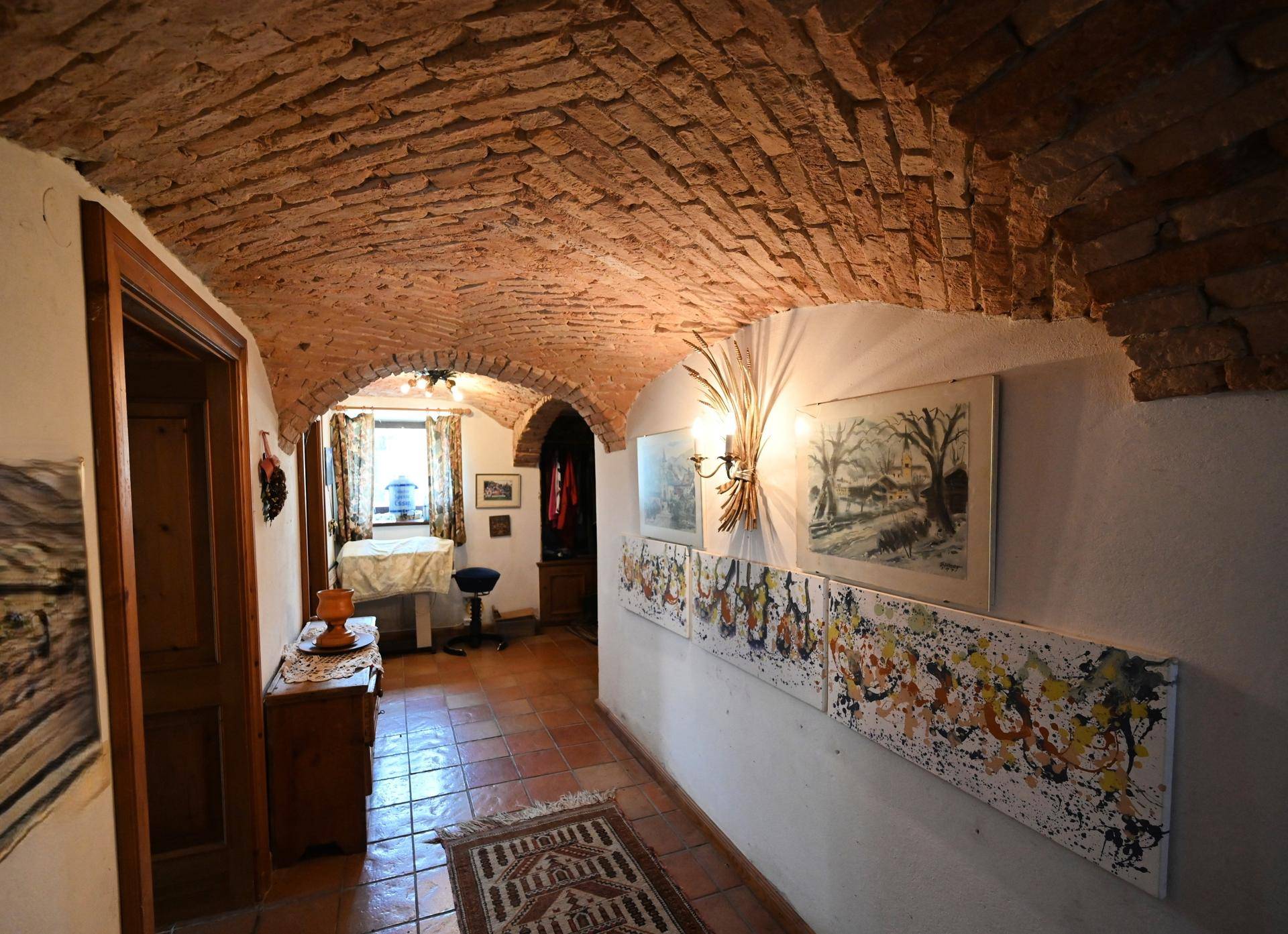 Historischer Flur mit beeindruckendem Ziegelgewölbe und traditionellen Kunstwerken an den Wänden.