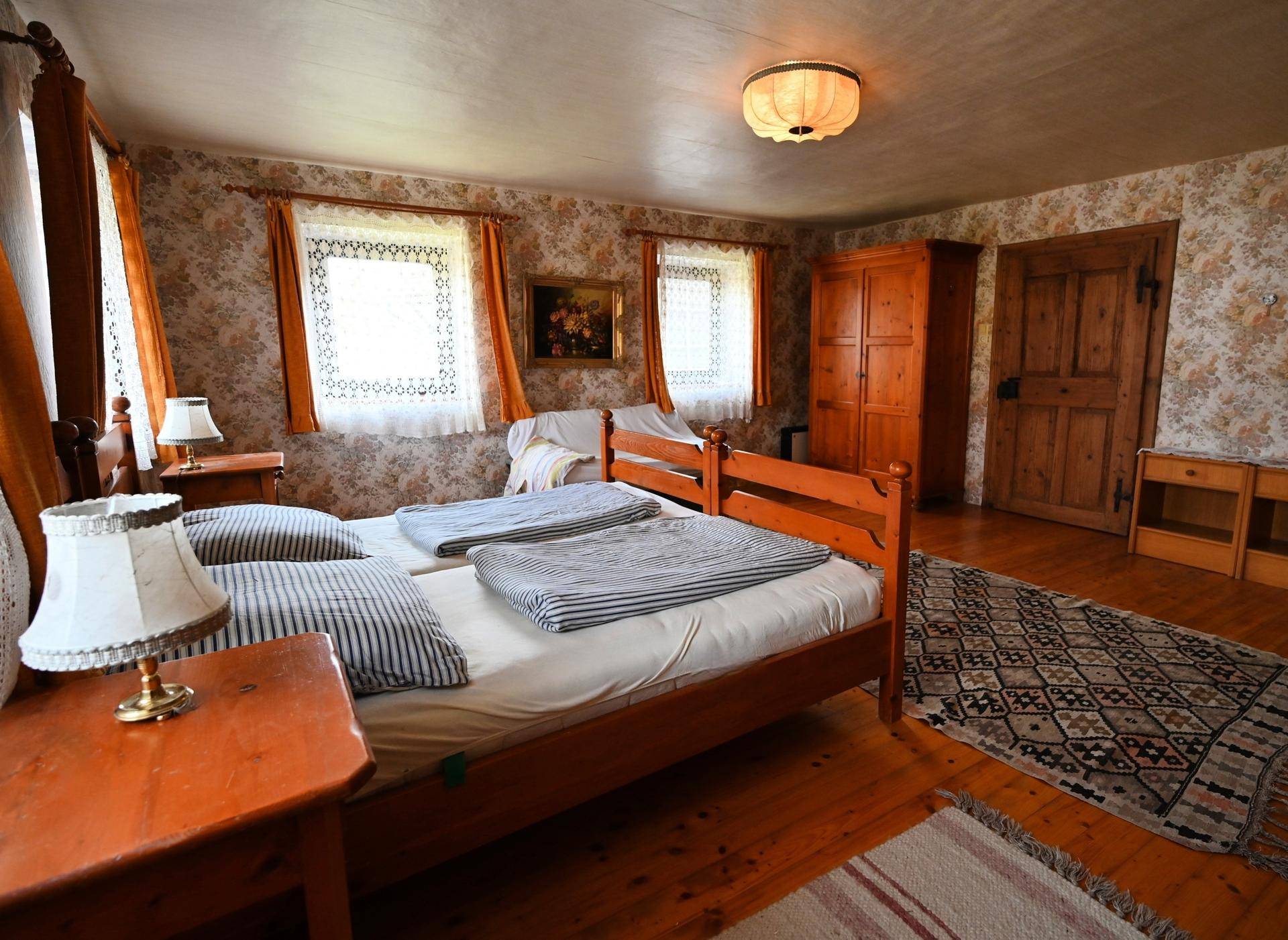Traditionelles Schlafzimmer mit floraler Tapete, Holzbetten und Dielenboden.