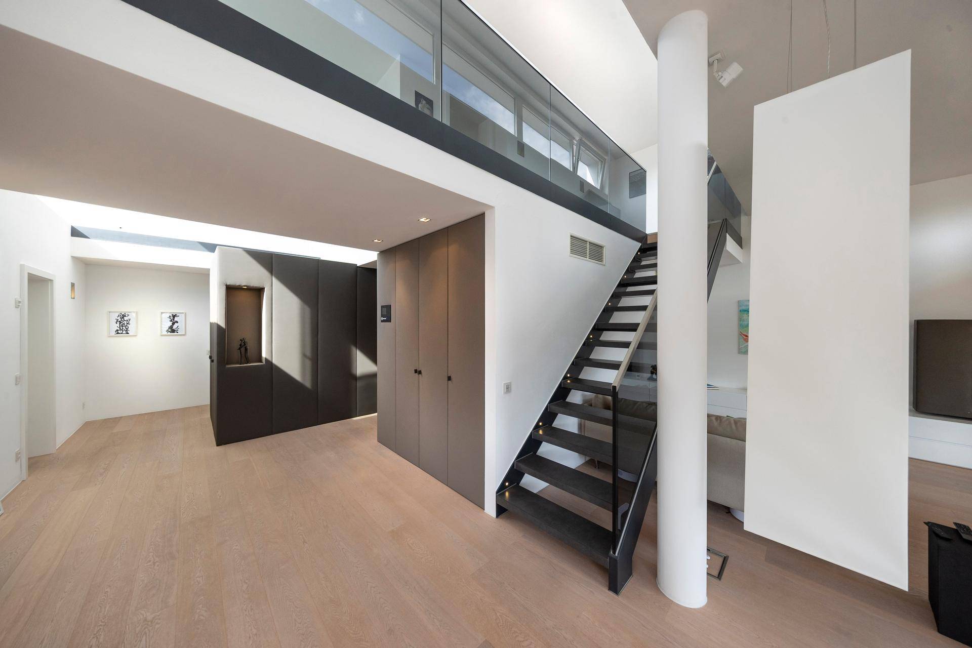 Heller, offener Wohnbereich mit moderner Treppe, Einbauschränken und viel Tageslicht.