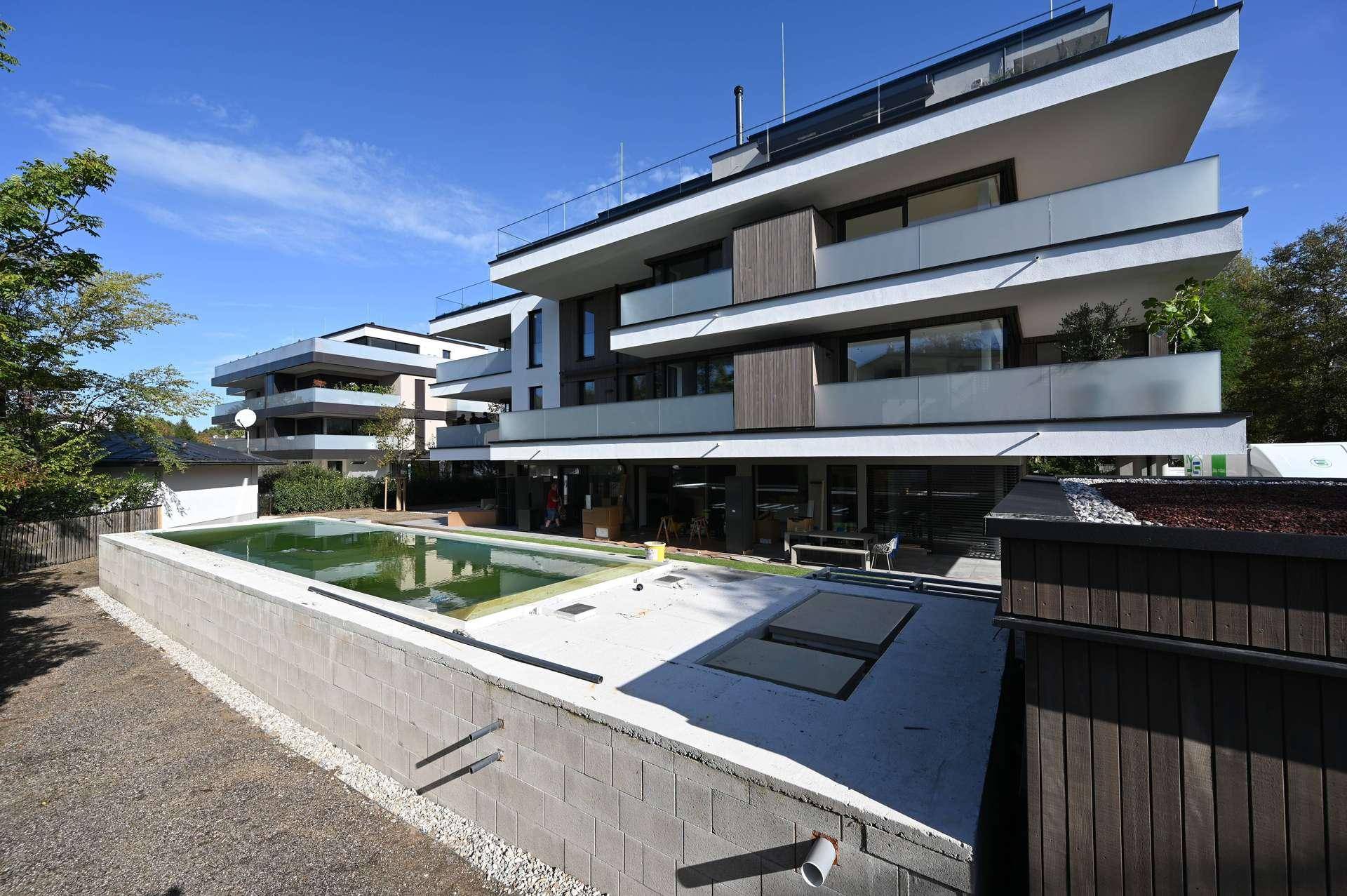Modernes Apartmentgebäude mit mehreren Balkonen und einem im Bau befindlichen Außenpoolbereich.