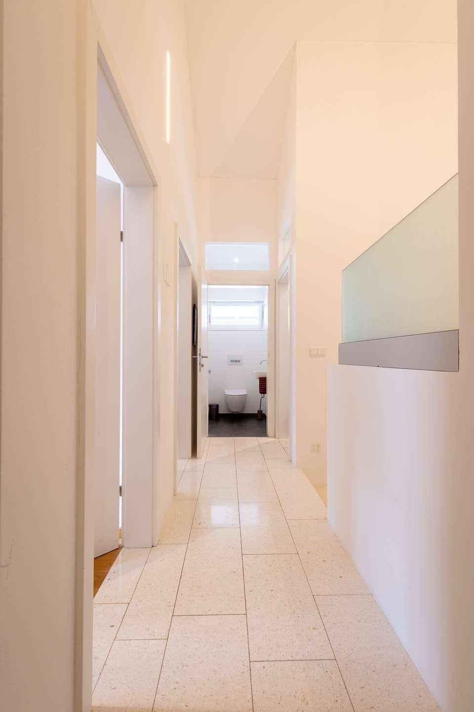Heller Flur mit Fliesenboden und Blick auf ein separates WC.