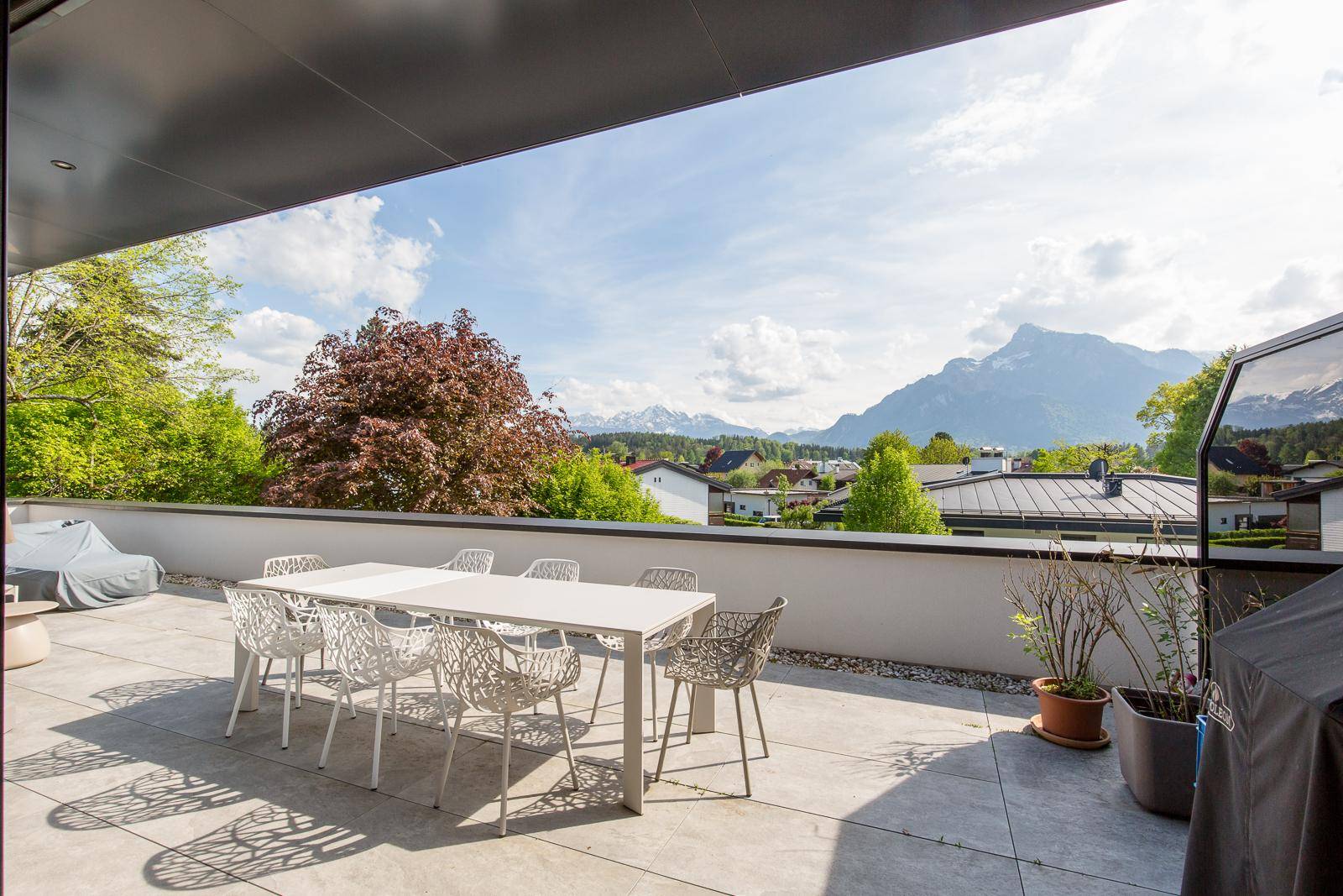 Geräumige Terrasse mit Essbereich und Grill, umgeben von grüner Landschaft und Bergblick.