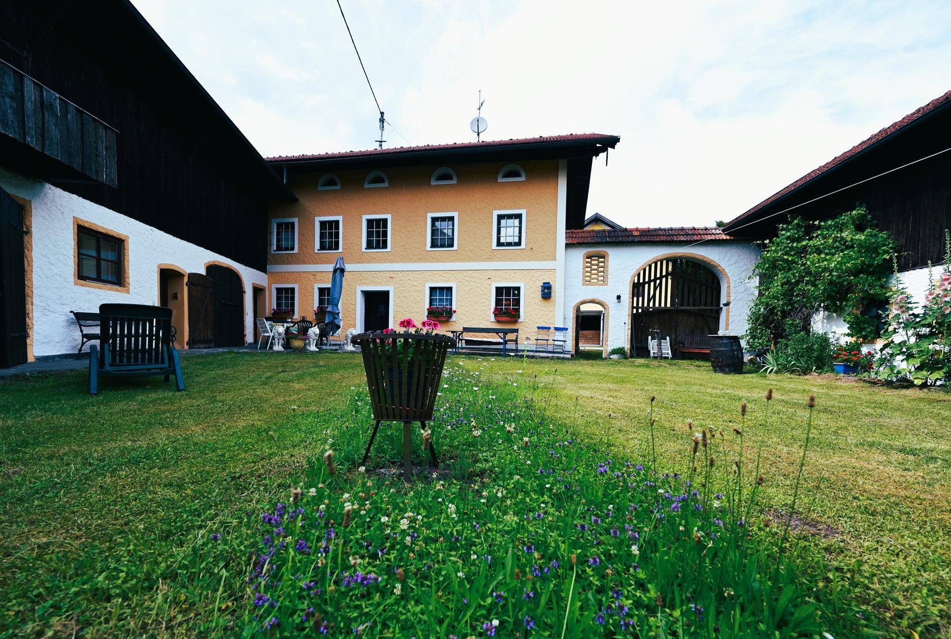 Großer grüner Innenhof mit Rasenfläche, umgeben von traditionellen Bauernhäusern.
