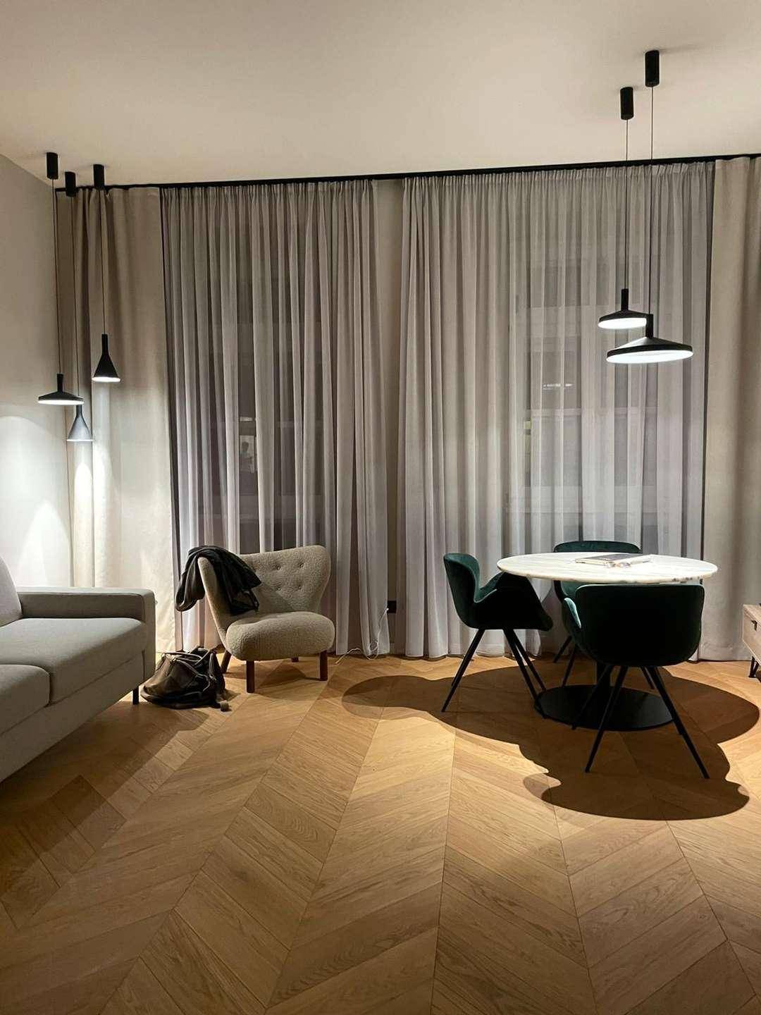 Geräumiger Wohn- und Essbereich mit Holzboden, modernen Möbeln und großen Fenstern.