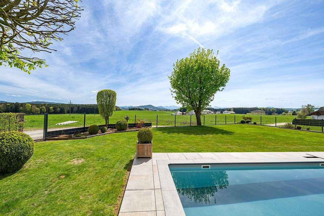 Weitläufiger grüner Garten mit einzelnen Bäumen und Panoramablick auf die umliegende Landschaft.