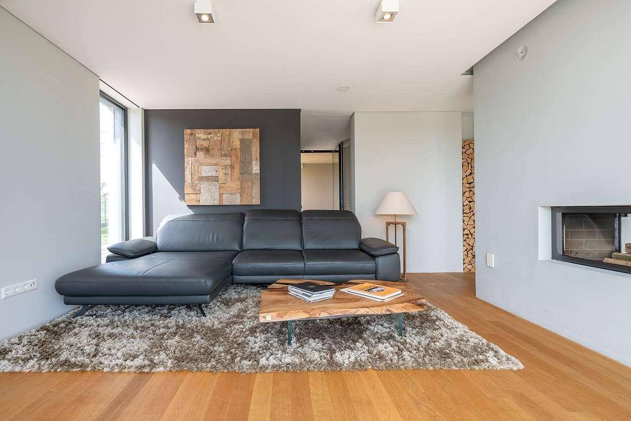 Modernes Wohnzimmer mit schwarzem Ledersofa, Holztisch und Kamin in heller Umgebung.