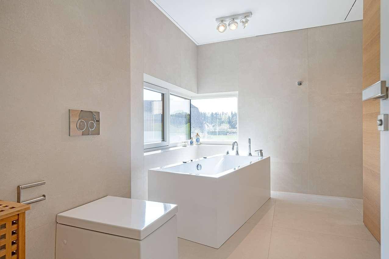 Helles Badezimmer mit freistehender Badewanne, modernem WC und Fenster für Tageslicht.