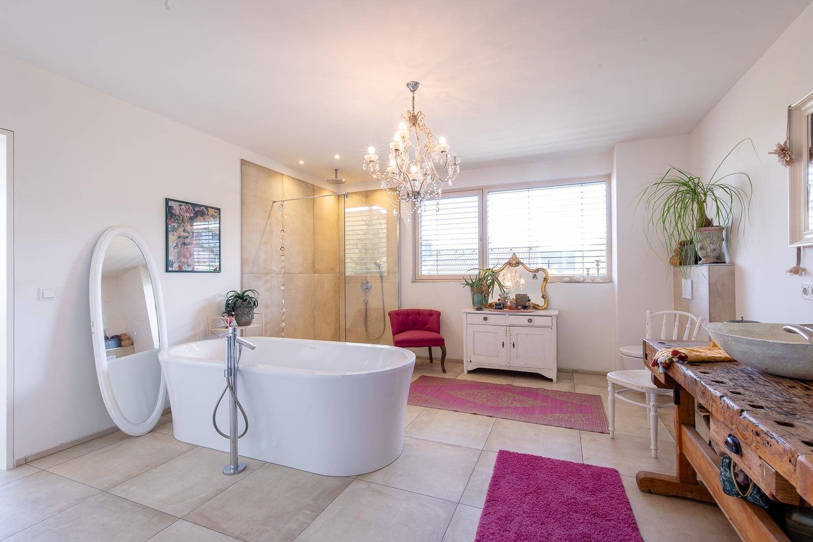 Luxuriöses Badezimmer mit freistehender Badewanne, großer Dusche und Kronleuchter.