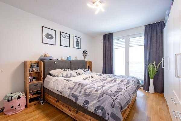 Gemütliches Schlafzimmer mit Doppelbett, Holzrahmen und Zugang zum Balkon oder zur Terrasse.