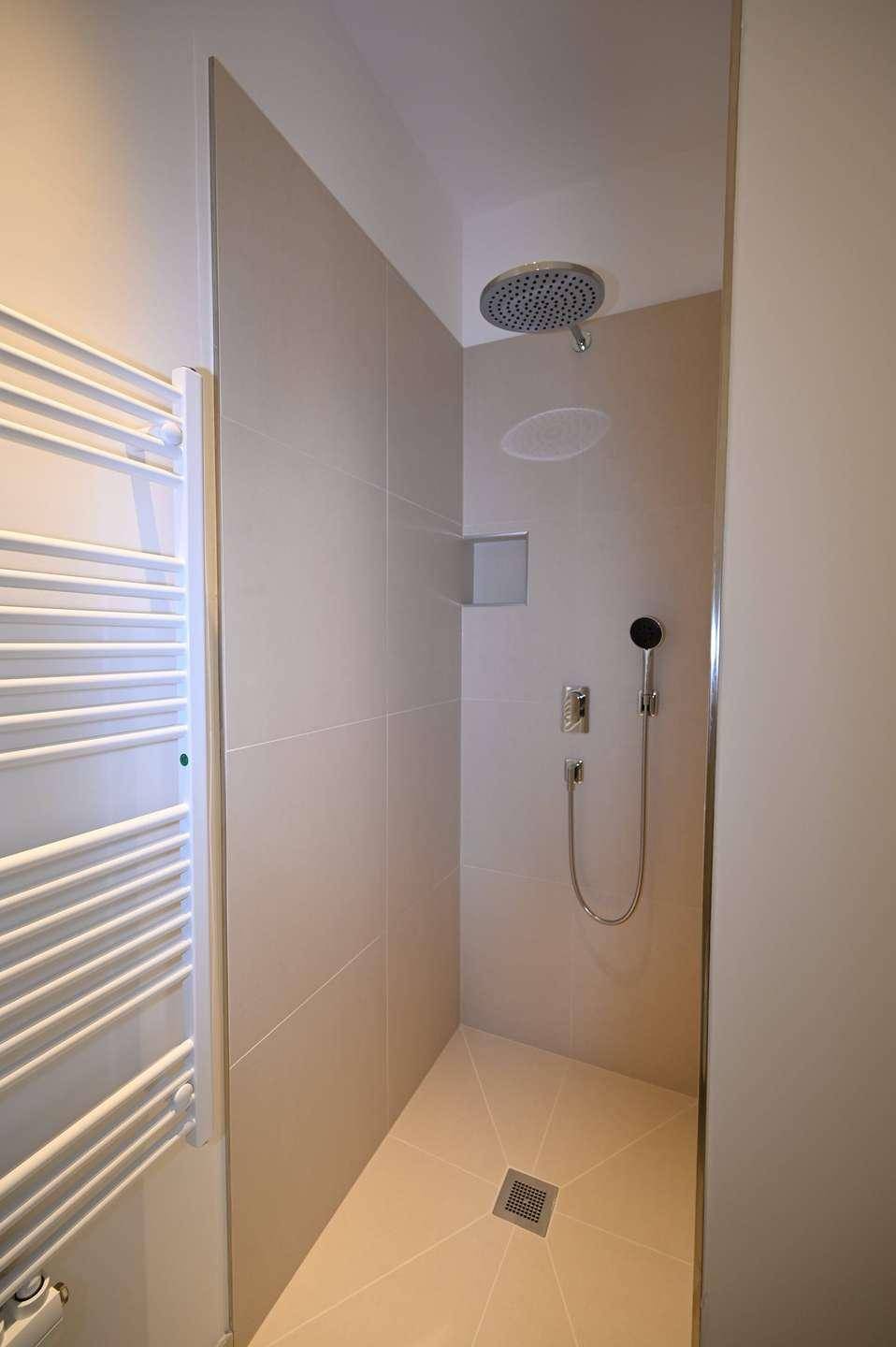 Moderne begehbare Dusche mit Regenduschkopf und praktischem beheiztem Handtuchhalter für Komfort.