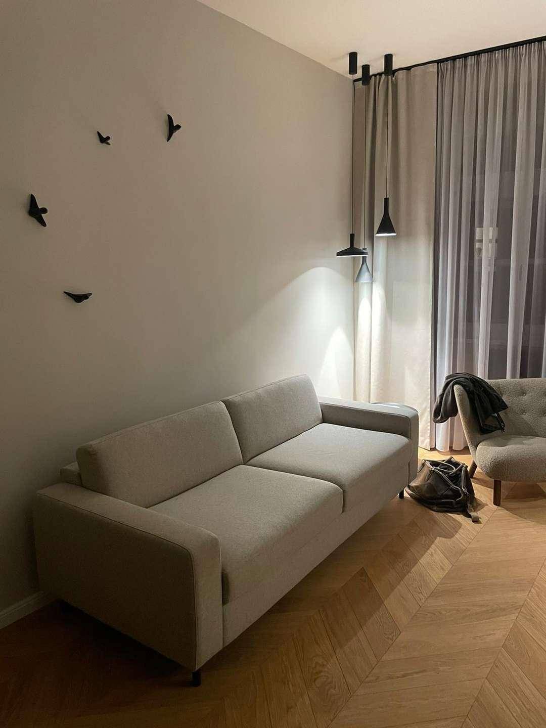 Helles Wohnzimmer mit bequemem Sofa, Sessel und dekorativen Wandelementen.