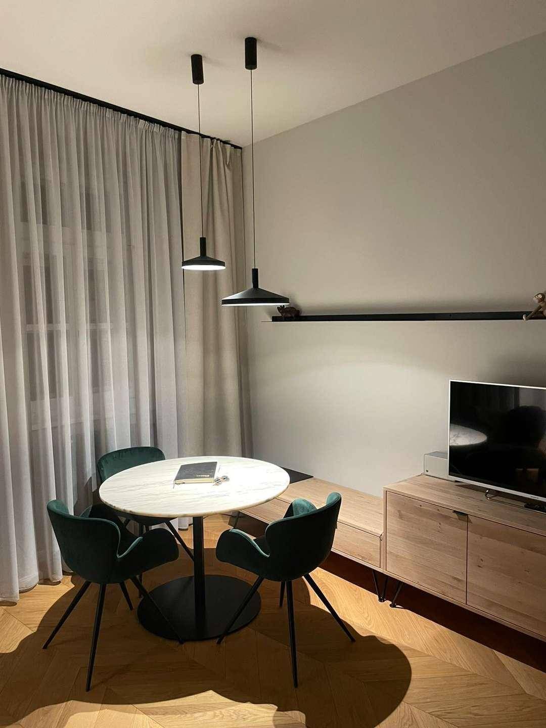 Moderner Essbereich mit Marmortisch und grünen Stühlen in einem hellen Raum.