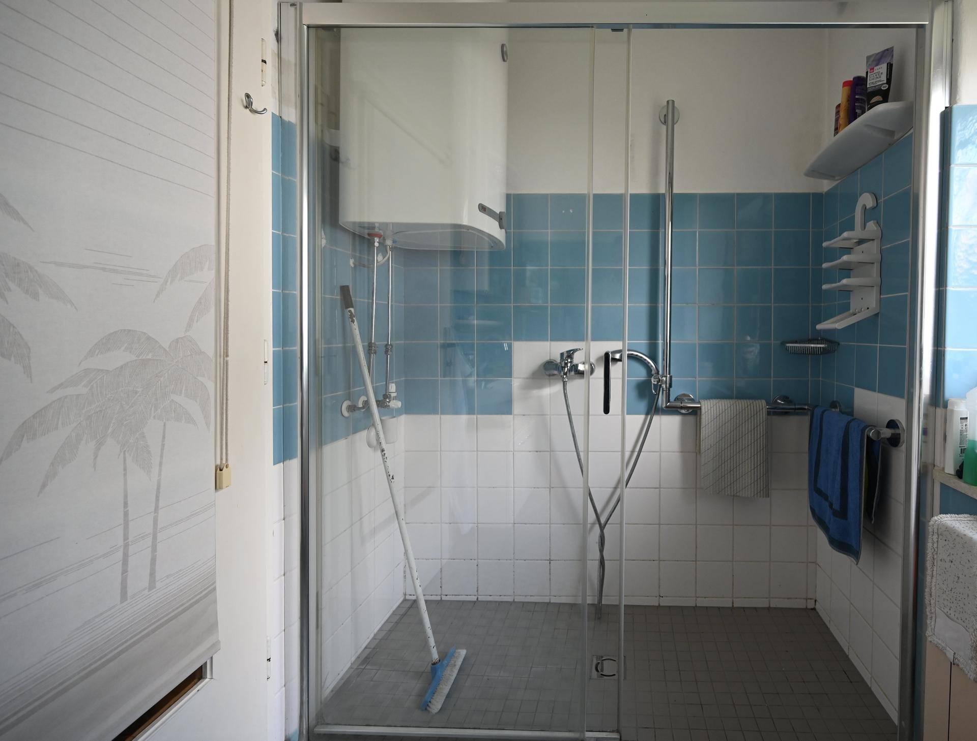 Badezimmer mit Duschkabine, blauen und weißen Fliesen, sowie Duscharmaturen.