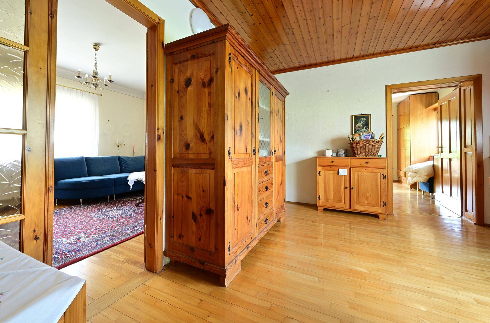 Offener Bereich mit Holzboden und Holzdecke, verbindet Ess- und Wohnzimmer.