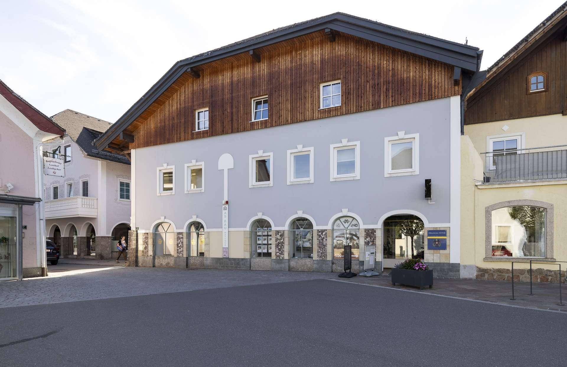 Traditionelles Gebäude mit gemischter Fassade aus Putz und Holz an einem Stadtplatz.