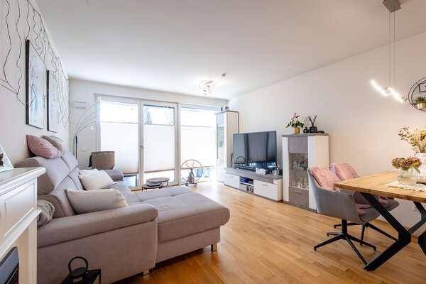 Offener Wohn- und Essbereich mit modernem Sofa, Esstisch und Zugang zum Außenbereich.