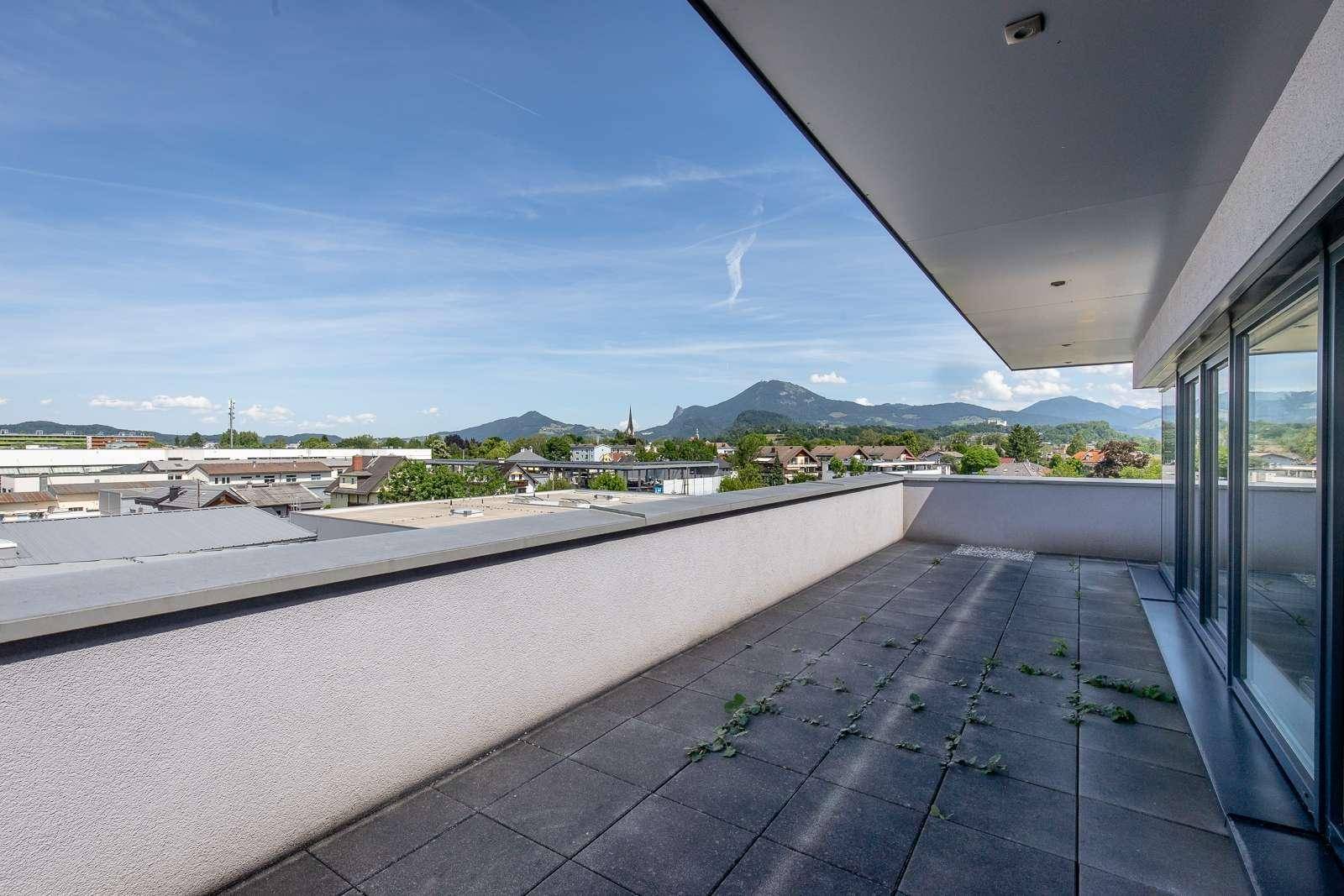 Geräumige Dachterrasse mit Fliesenboden und weitem Blick auf die Berge und die Stadt.
