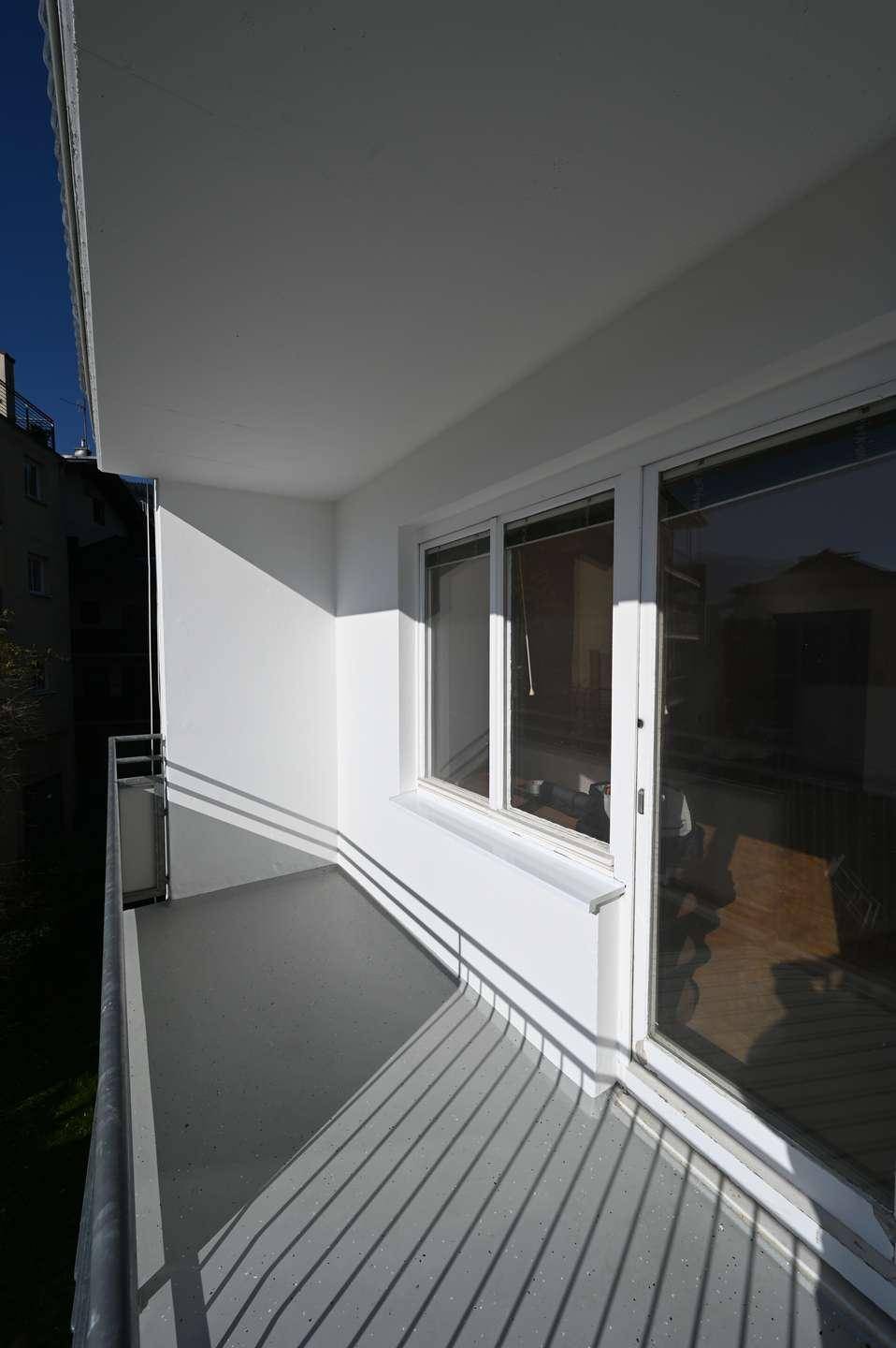 Heller, leerer Balkon mit Metallgeländer und Blick auf die Umgebung.