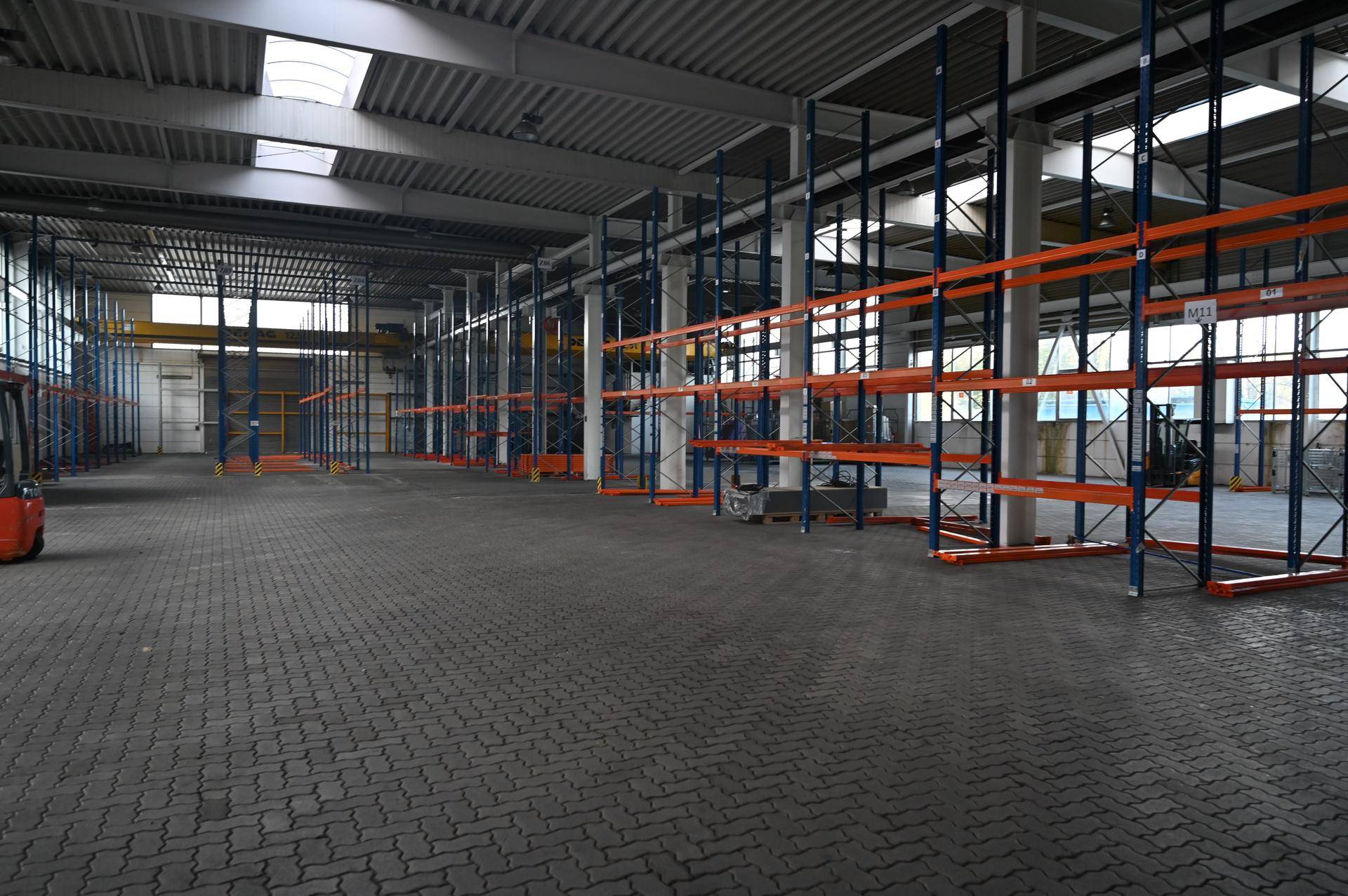 Geräumige Lagerhalle mit hohen Decken, Regalsystemen und einem Gabelstapler.
