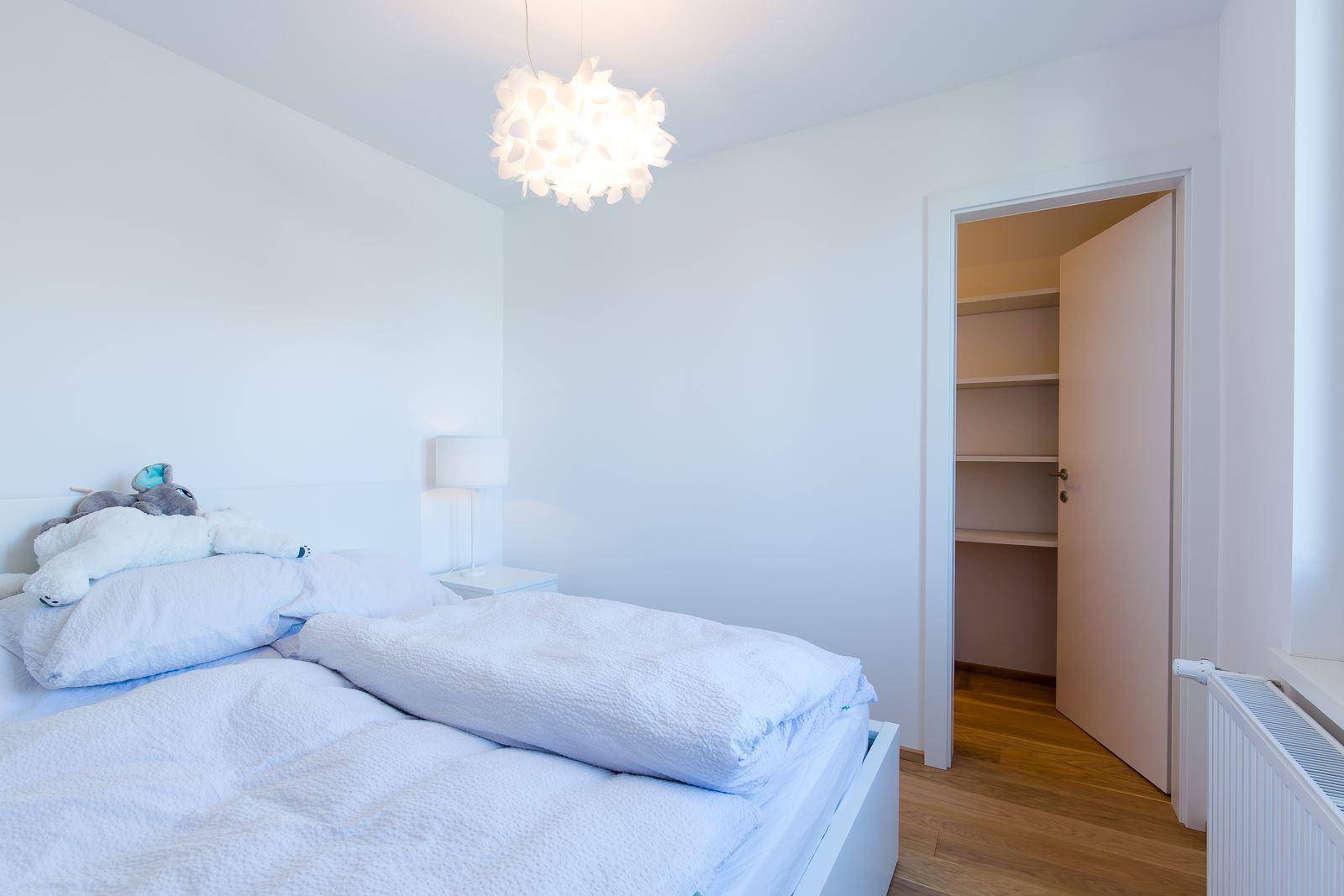 Helles Schlafzimmer mit Holzboden und Zugang zu einem begehbaren Kleiderschrank.