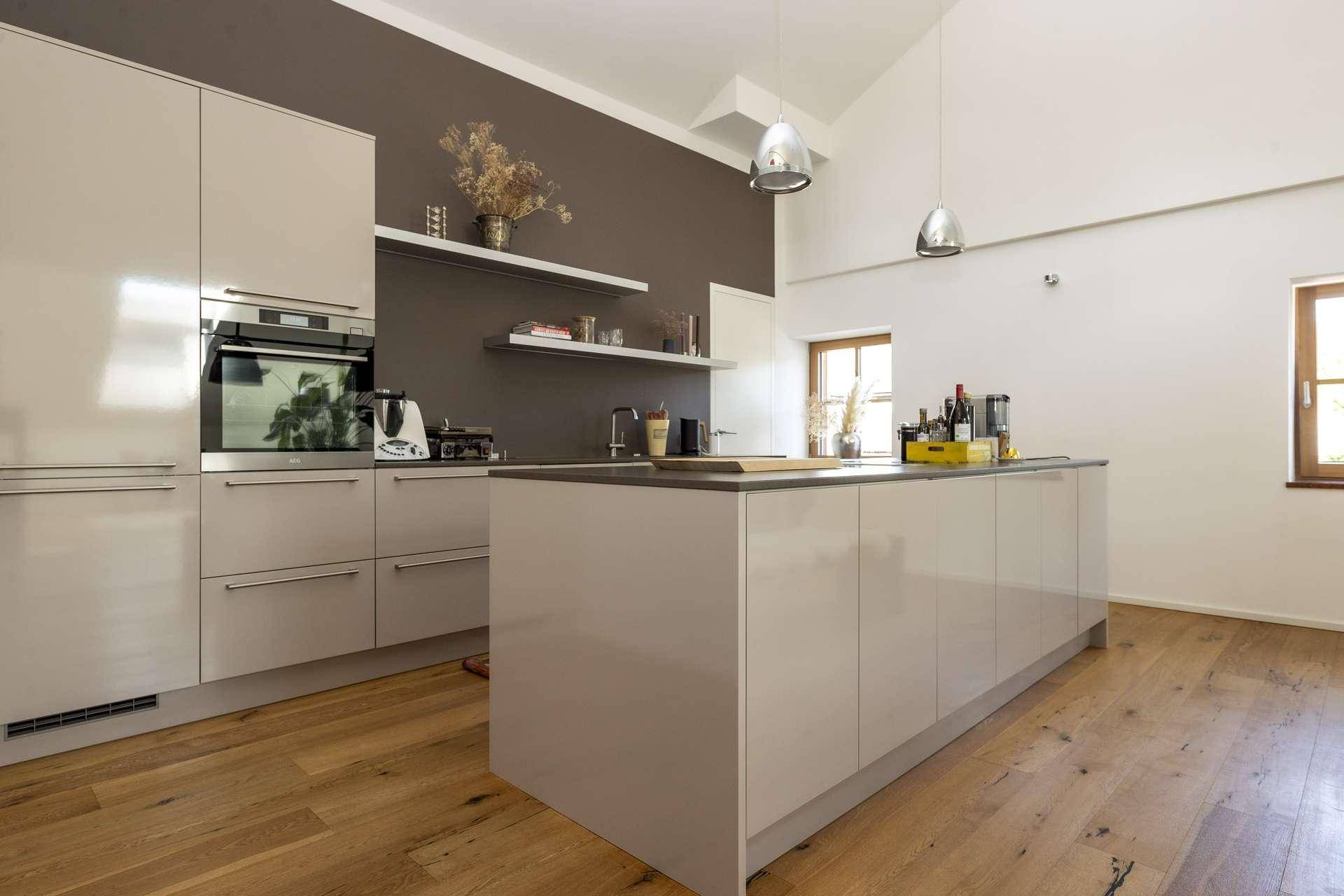 Moderne Einbauküche mit Kücheninsel, integrierten Geräten und stilvoller Beleuchtung.
