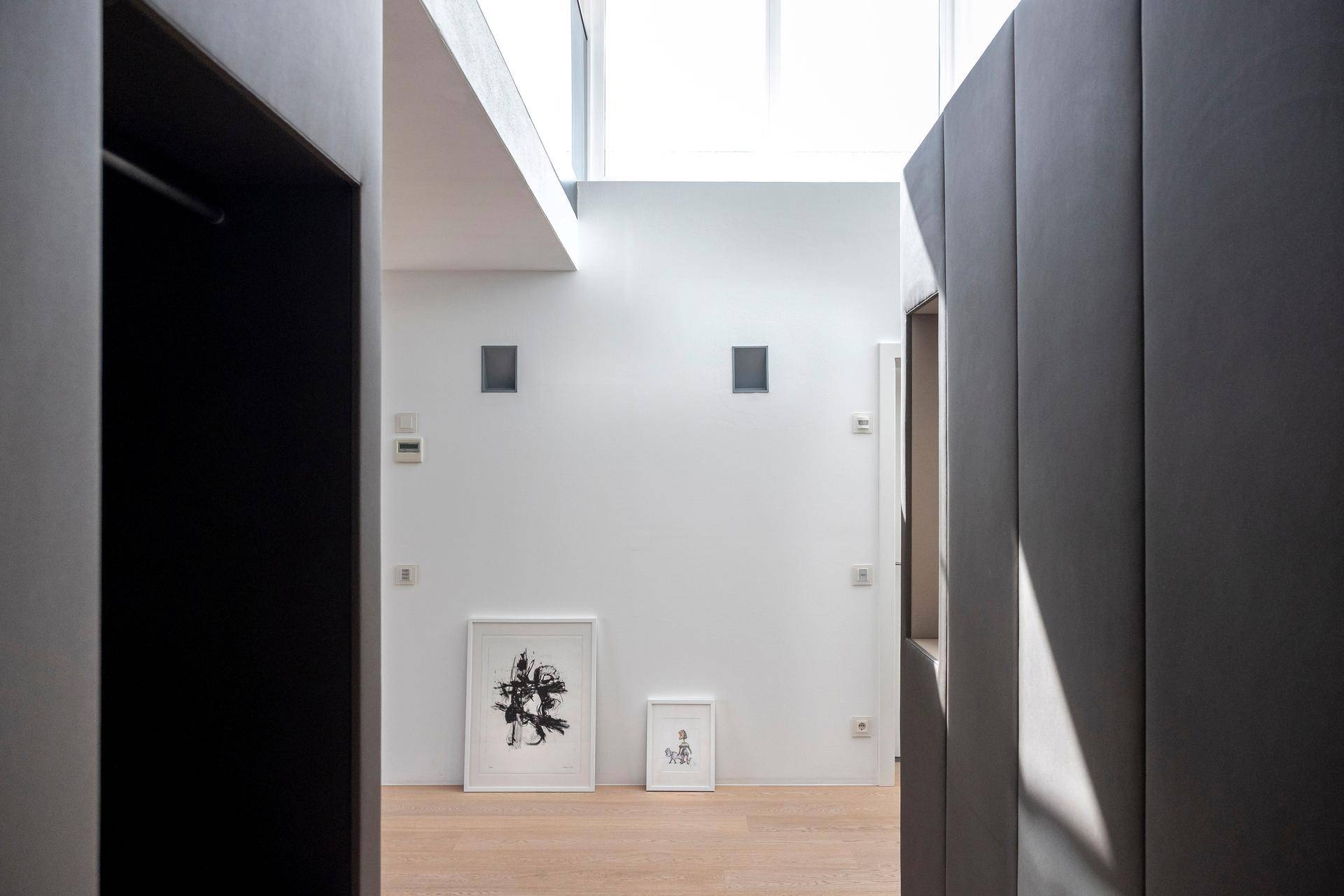 Heller Flur mit modernen Kunstwerken, Einbauschränken und viel natürlichem Licht.