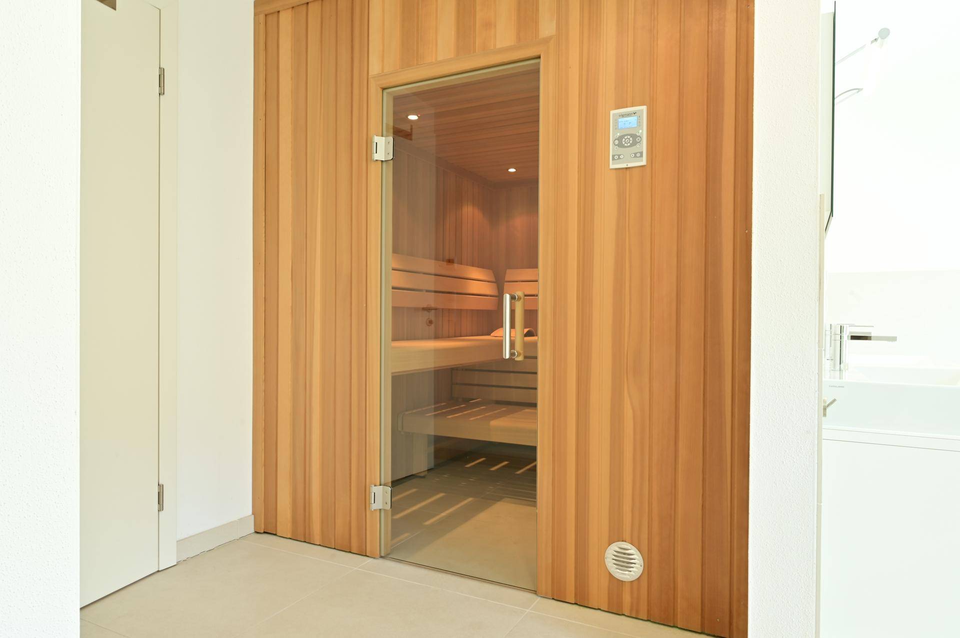 Hochwertige Holzsauna mit Glastür, bereit für entspannende Wellness-Momente im eigenen Zuhause.
