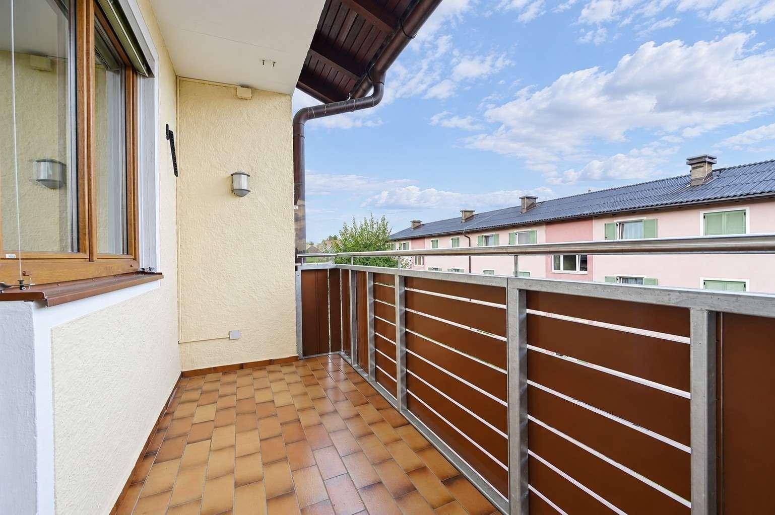 Balkon mit Fliesenboden und modernem Geländer, bietet Blick auf die Nachbarschaft.