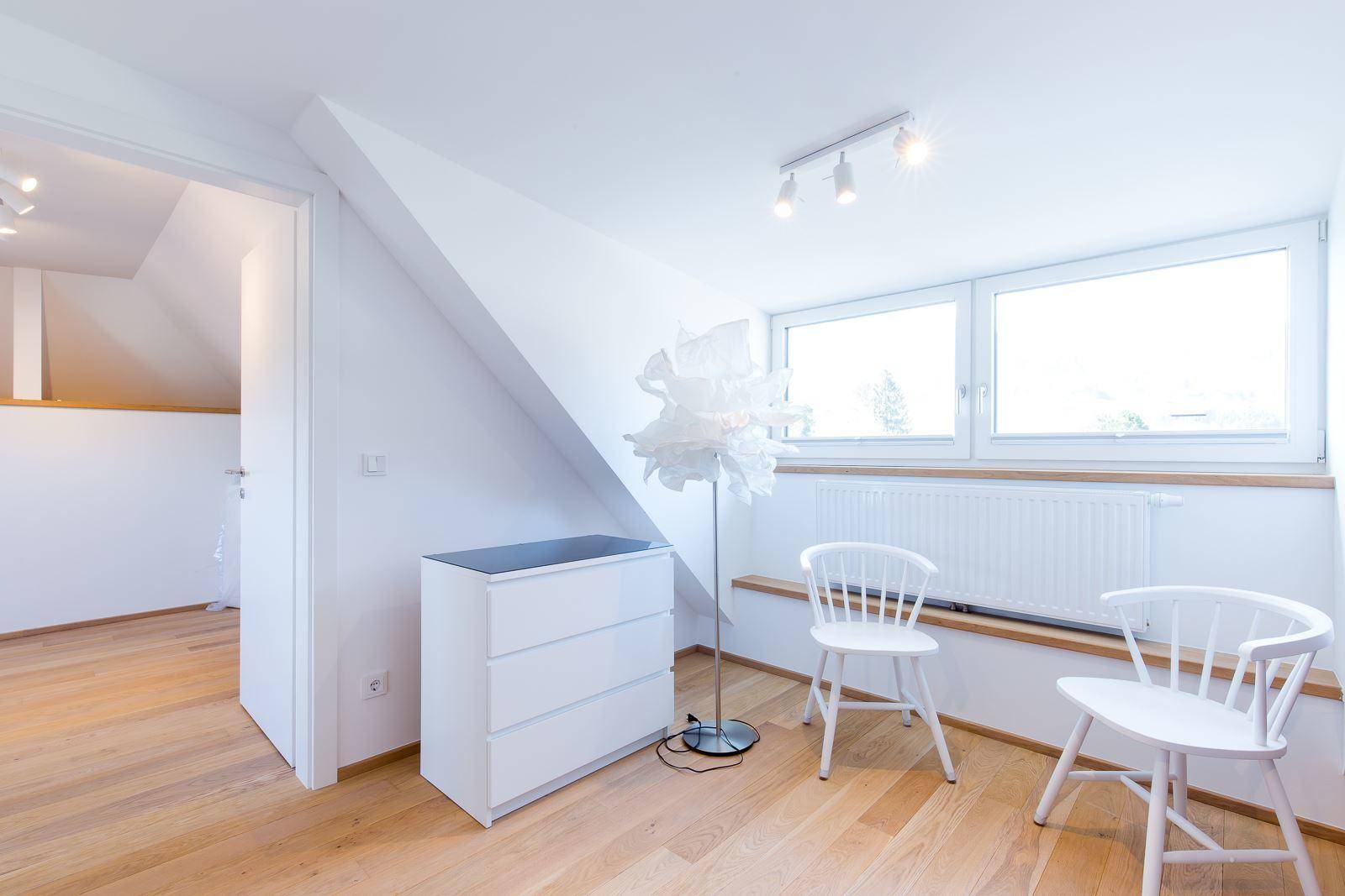 Helles Schlafzimmer im Dachgeschoss mit Holzboden, Dachschräge und großen Fenstern.