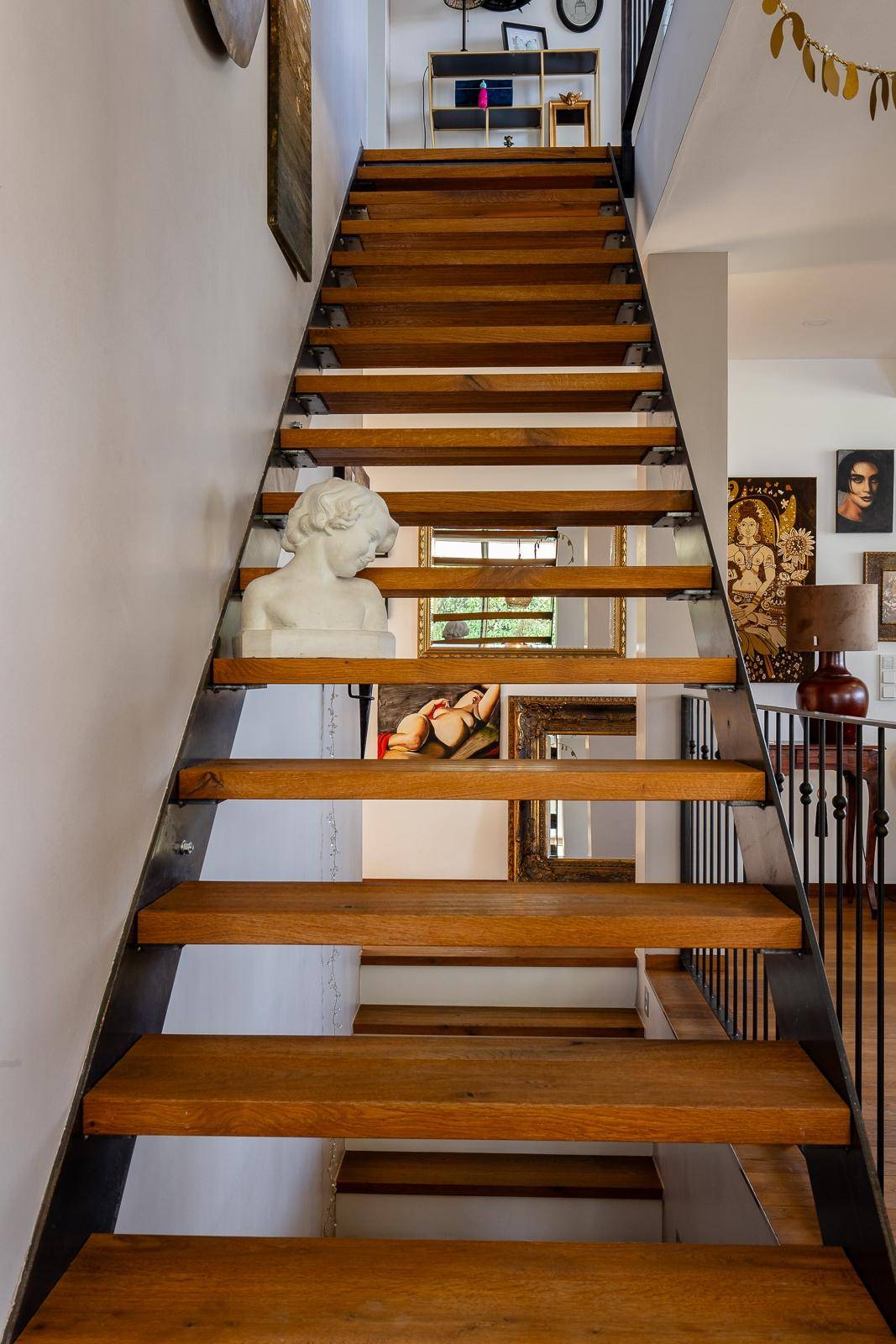 Elegante Holztreppe mit Metallgeländer und dekorativen Elementen in einem hellen Flur.