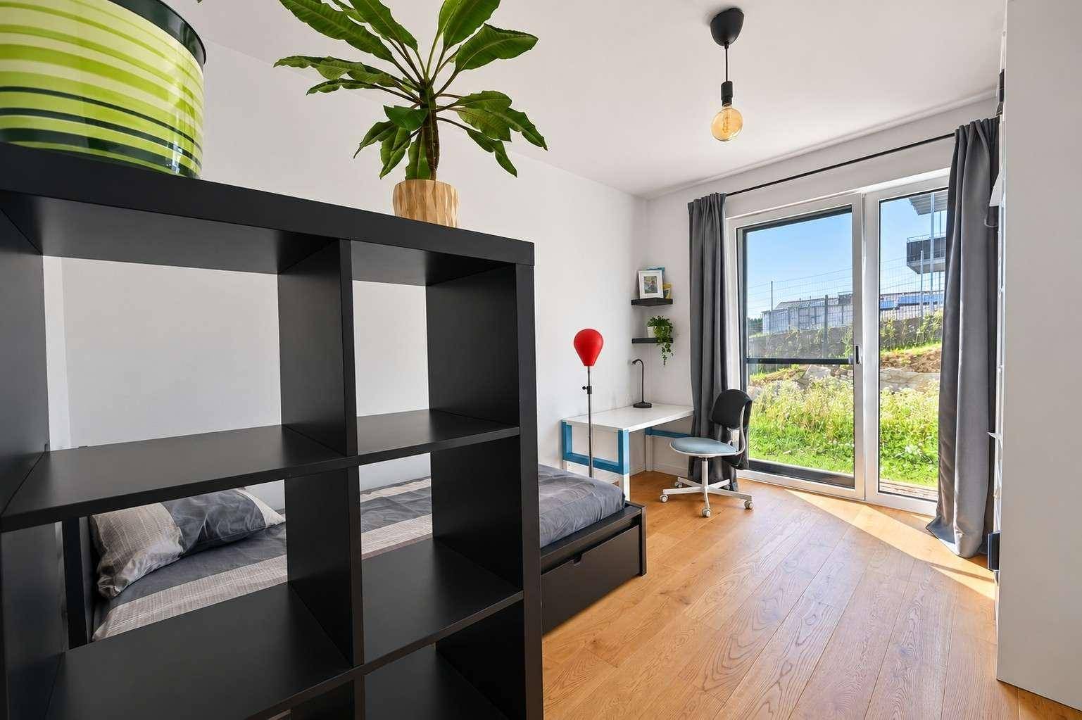 Jugendzimmer oder Büro mit Holzboden, Schreibtisch und großem Fenster mit Blick ins Grüne.
