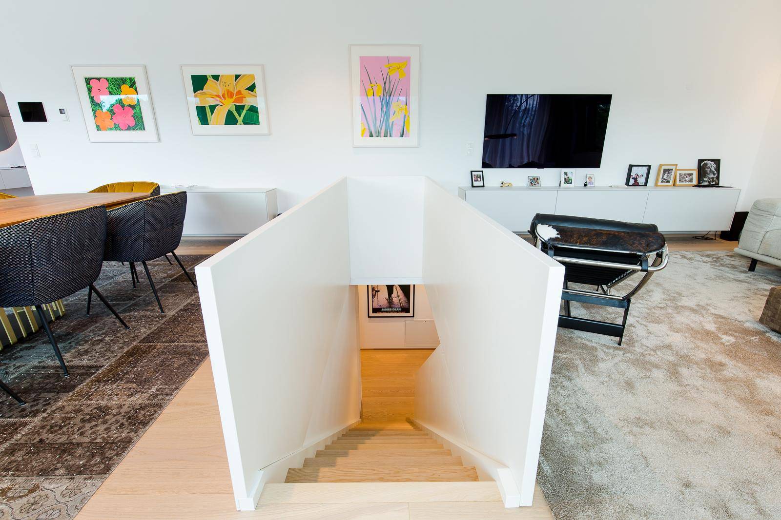Geräumiger Wohnbereich mit Treppe, Kunstwerken und Blick auf den Essbereich, hell und offen gestaltet.