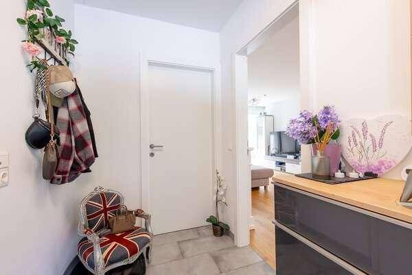 Heller Eingangsbereich mit Fliesenboden, Garderobe und dekorativem Stuhl.