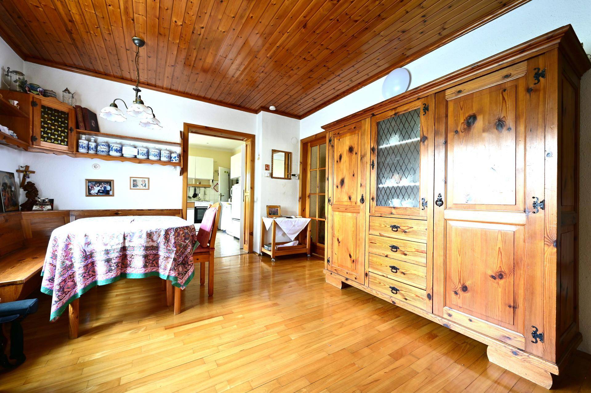 Rustikaler Essbereich mit Holztisch, Eckbank, großem Holzschrank und Holzdecke.