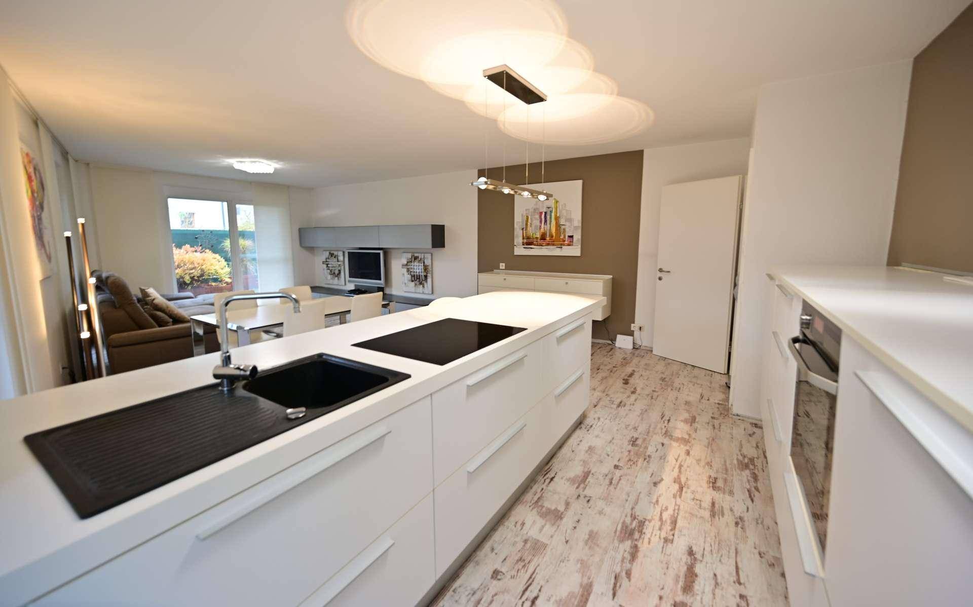 Helle Einbauküche mit moderner Kochinsel, integriertem Kochfeld und Backofen.