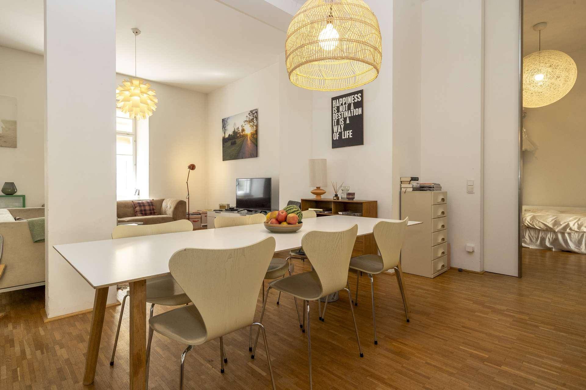Heller Essbereich mit großem Esstisch und modernen Stühlen, offen zum Wohnzimmer.
