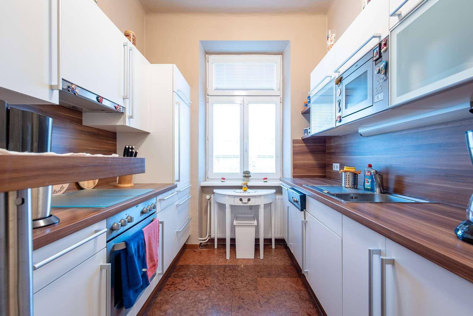 Funktionale Küche mit weißen Schränken, Holz-Arbeitsplatten und Fenster.