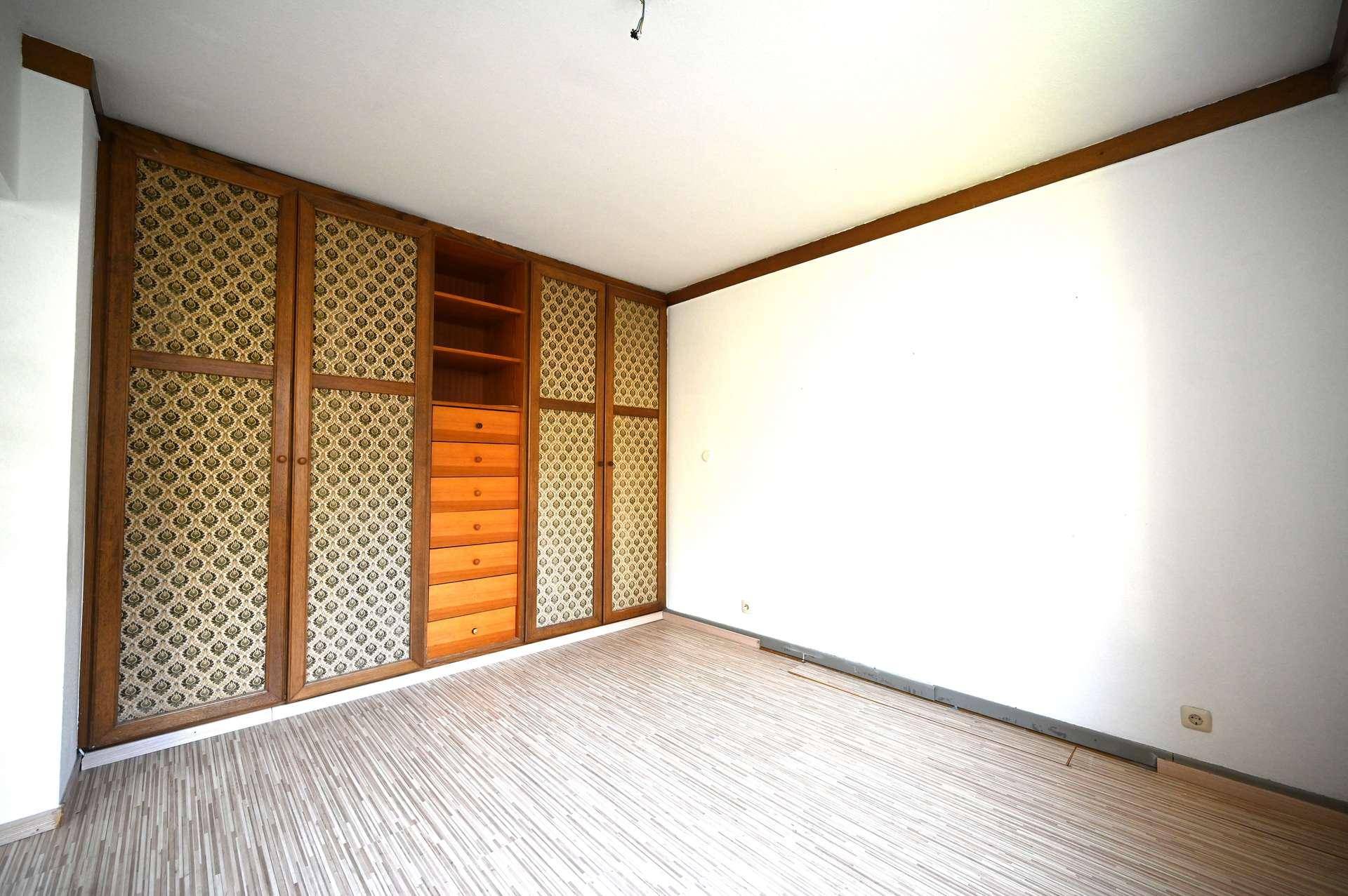 Geräumiges Schlafzimmer mit integrierten Holzschränken und hellem Bodenbelag.