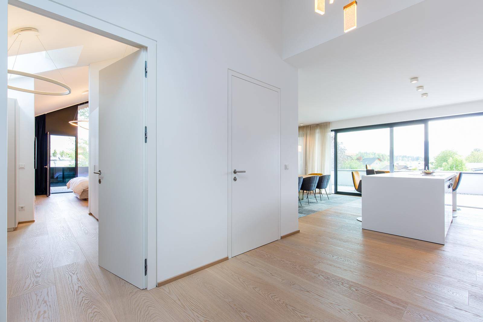 Heller Flur mit Holzboden, der verschiedene Wohnbereiche und ein Schlafzimmer verbindet.