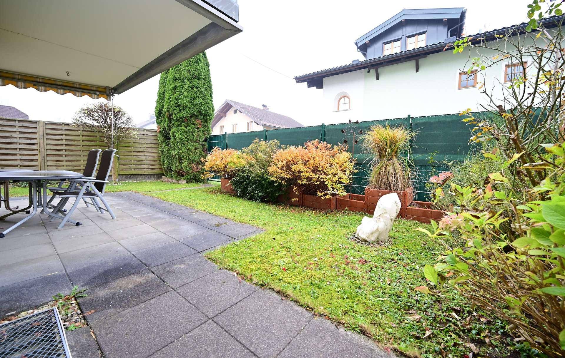Gepflasterte Terrasse mit Gartenmöbeln und angrenzender Rasenfläche.